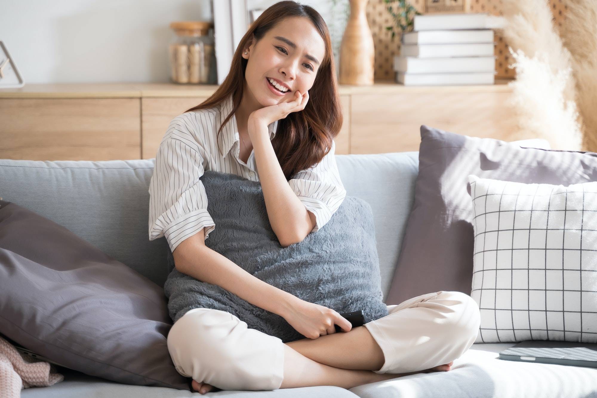 Asian woman happily watch tv comedy series on sofa living room at home